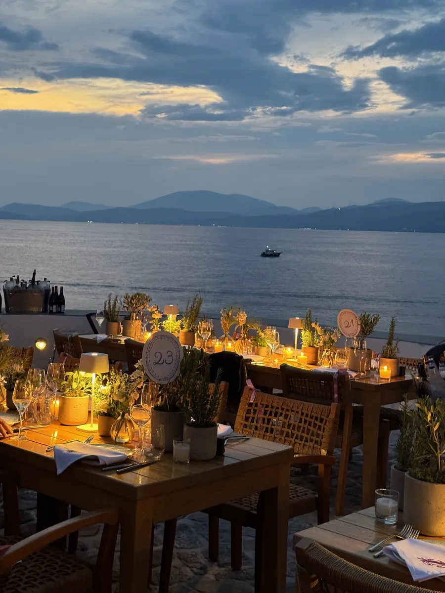 Candlelit tables on a terrace above the sea at dusk