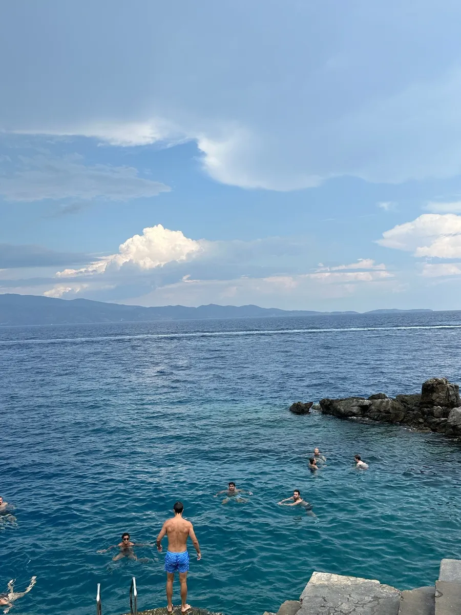 Swimmers jumping off the rocks into the sea
